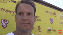 a man stands in front of a yellow wall that says trojan
