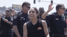 a group of police officers are standing around a woman wearing a rainbow shirt .