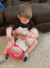 a boy with the word nike on his shirt is feeding a baby