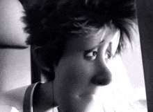 a black and white photo of a woman looking out a window with headphones on