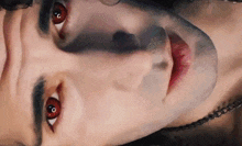 a close up of a man 's face with red eyes and black eyebrows .