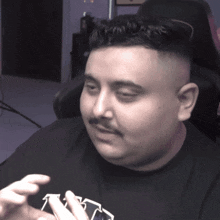 a man with a mustache is wearing a black shirt that says t on it