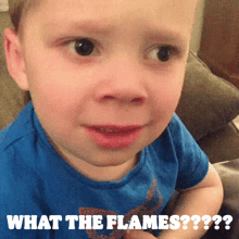a young boy in a blue shirt is making a funny face with the words what the flames written below him .