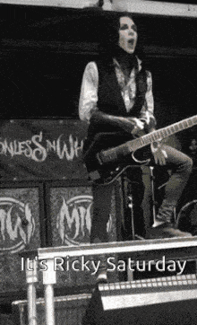 a man playing a guitar on a stage with the words it 's ricky saturday on the bottom