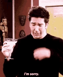 a man is holding a martini glass and crying while saying i 'm sorry .