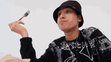 a man wearing a black hat is holding a fork in his right hand