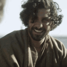 a man with curly hair and a beard smiles at the camera