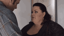 a man and a woman are standing next to each other and the woman is looking at the man .