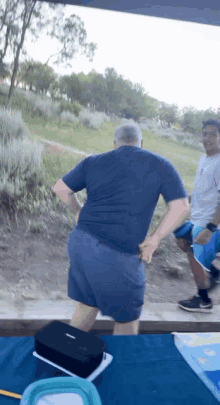 a man in a blue shirt and blue shorts is standing on a table