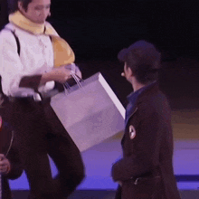 a man is holding a shopping bag while standing next to another man on a stage .