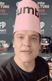 a man wearing a pink paper hat with the word thumbs on it