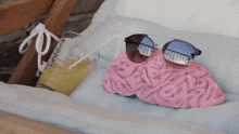 a brain shaped pillow with sunglasses and a glass of orange juice with a straw