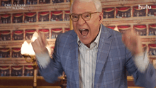a man in a suit and glasses is screaming in front of a wall that says hulu