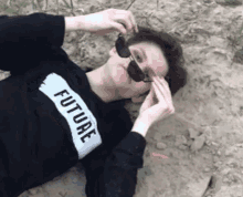a person wearing sunglasses and a black sweater that says future