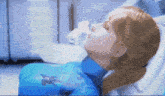 a woman in a blue suit is laying in a hospital bed with an oxygen mask on her face