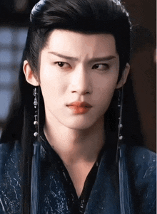 a close up of a man 's face with long black hair and earrings