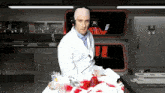 a man in a lab coat with a bandage on his head stands in front of a display that says ' j '