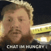 a man with a beard says chat im hungry in front of a waffle house