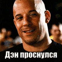 a bald man is smiling in front of a sign that says " dzn proshuyus "