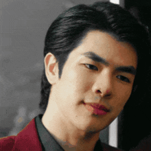 a close up of a man 's face with a red jacket and green shirt