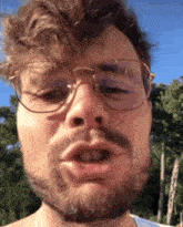 a man with a beard and glasses is making a face .