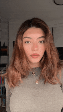 a woman with long brown hair wearing a grey sweater