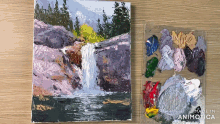 a painting of a waterfall is next to a palette