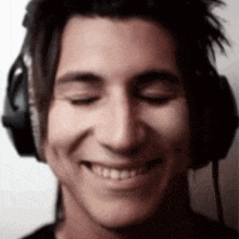 a close up of a man wearing headphones smiling