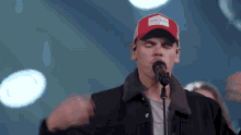 a man wearing a red hat that says calvin klein on it sings into a microphone