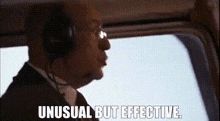 a man in a suit and tie is wearing headphones and looking out the window of an airplane .