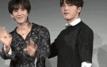 two young men are standing next to each other clapping their hands