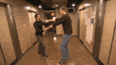 two men are dancing in a hallway with a red exit sign in the background