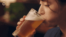 a woman is drinking a glass of beer with a sticker that says ' a ' on it