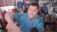 a man wearing a blue tie dye shirt is sitting in front of a wall with jerseys on it including one that says 99