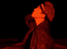 a man wearing a headband is standing in a dark room with a red light behind him .