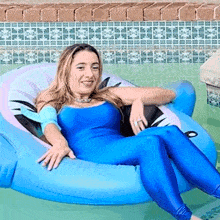 a woman in a blue bodysuit is laying on an inflatable dolphin in a swimming pool