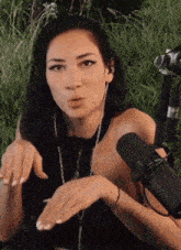 a woman is sitting in the grass with a microphone behind her