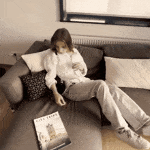 a woman sits on a couch with a city trips magazine