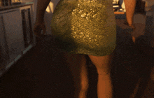 a woman in a green dress stands in front of a window