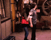 a man and a woman are hugging in a room with a sign that says danger