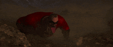 a man in a red superhero outfit is crawling on the ground