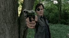 a man with an eye patch is pointing a gun at the camera .