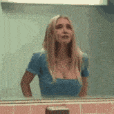 a woman is standing in front of a mirror in a bathroom .