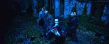 a group of people are standing next to each other in a forest at night .