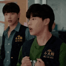 two young men are standing next to each other and one is wearing a vest with chinese writing on it .