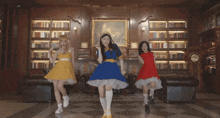 three girls are dancing in a room with a clock on the wall