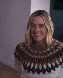 a woman wearing a sweater with a pattern on it smiles