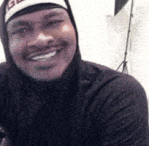 a man wearing a black hoodie and a hat with the letter g on it