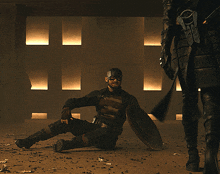 a man in a superhero costume is kneeling down with a shield in his hand