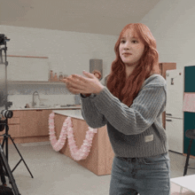 a woman in a grey sweater is clapping her hands